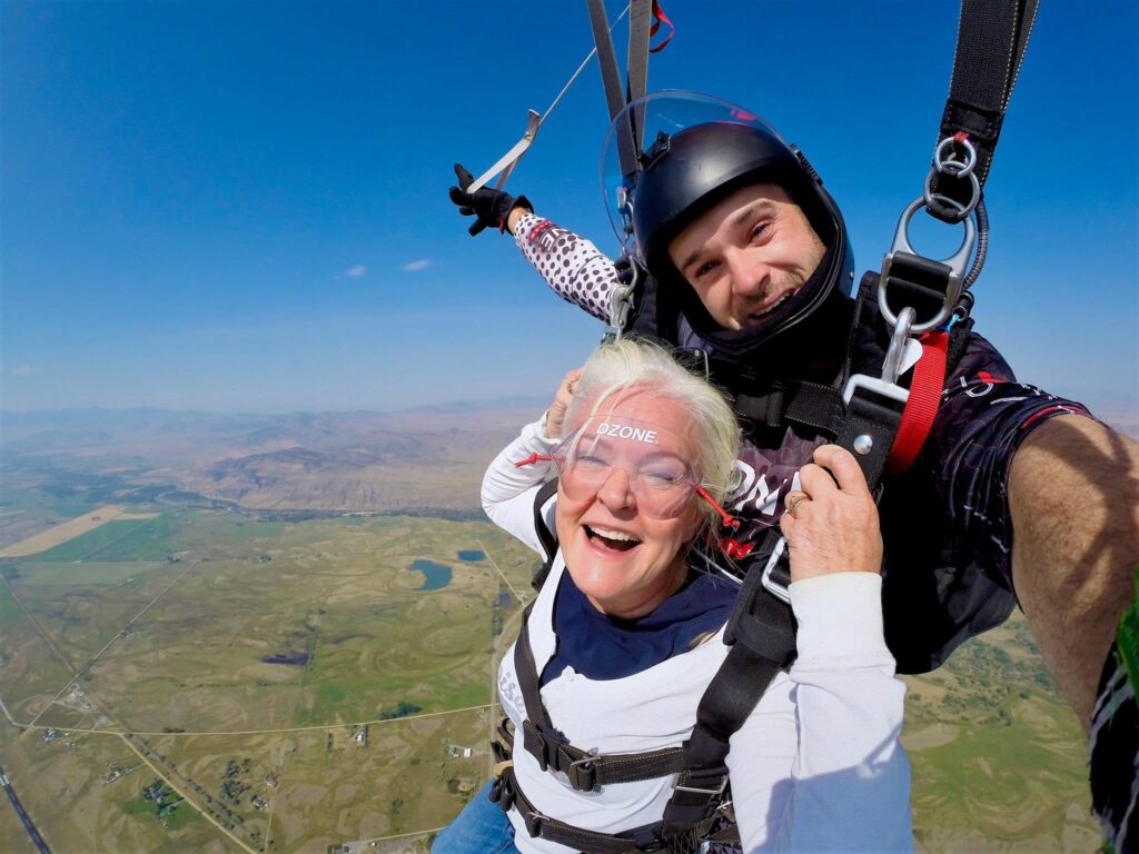 A lady smiles while flying under parachute.
