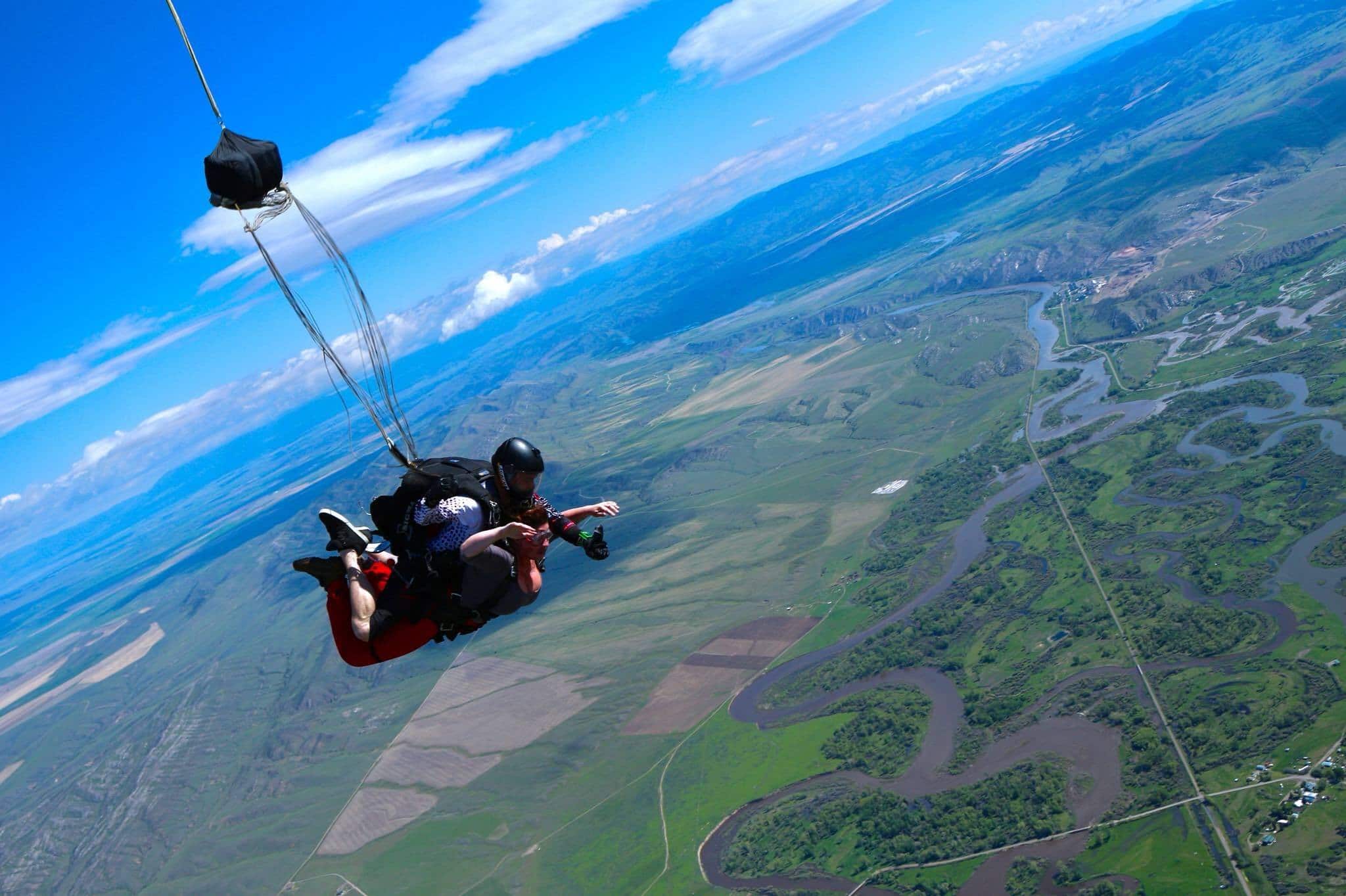 MT13 Tandem instructor and female student in freefall above green landscape
